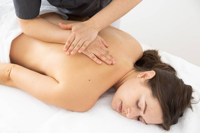 Eine Person, die auf dem Bauch liegend auf einer professionellen Massageliege eine Rückenmassage erhält.