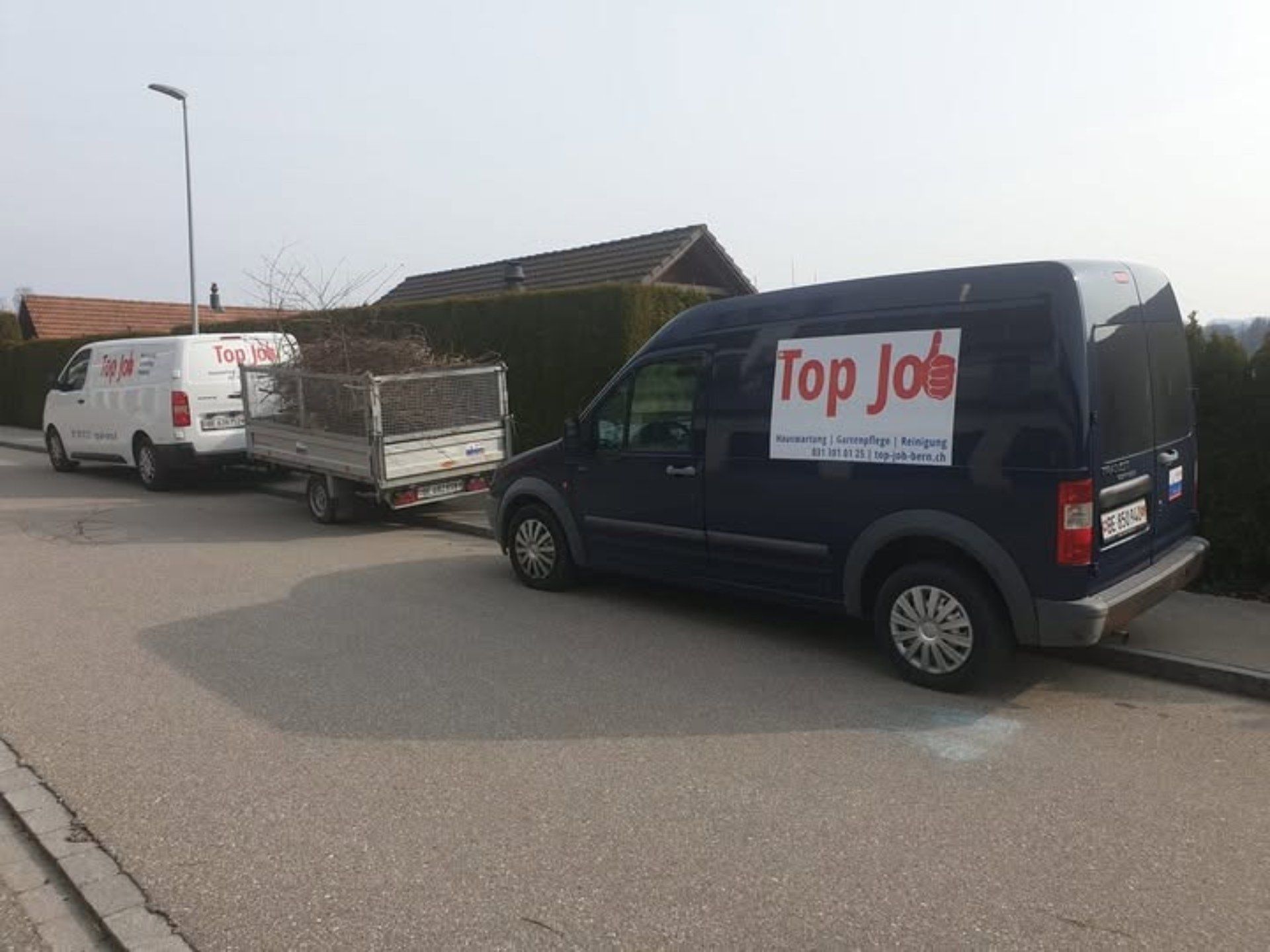 Zwei Lieferwagen, einer weiss und einer dunkelblau, parkten auf einer Strasse