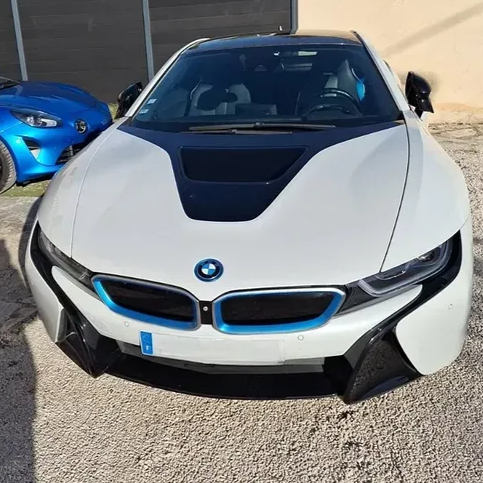 BMW i8 blanche garée à l'extérieur, vue de face, à côté d'une voiture de sport bleue