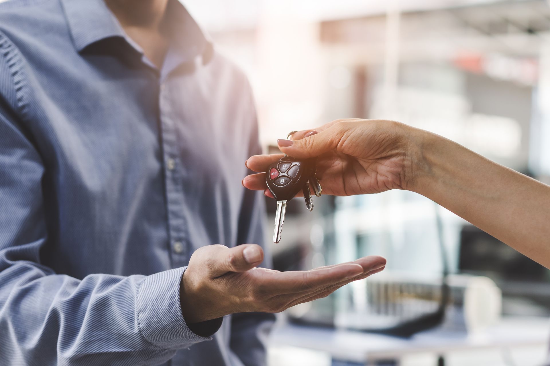 Remise de clés de voiture d'une personne à une autre dans un cadre de bureau lumineux
