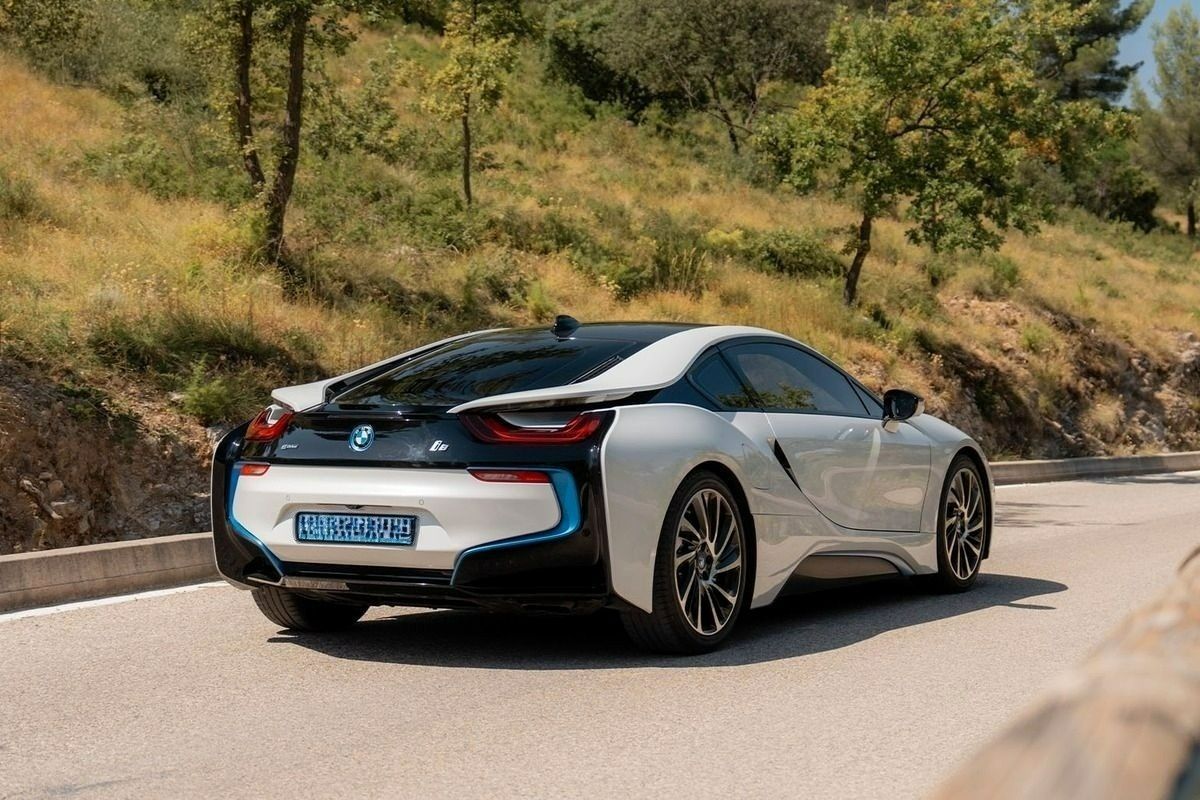 Voiture de sport blanche roulant sur une route de montagne sinueuse bordée de verdure