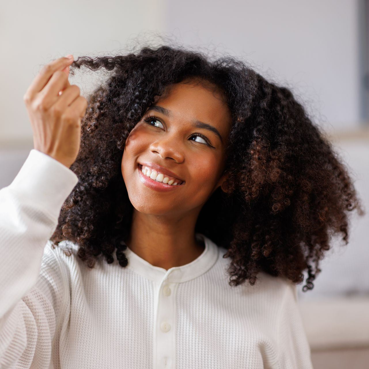 Une femme souriante regardant ses cheveux