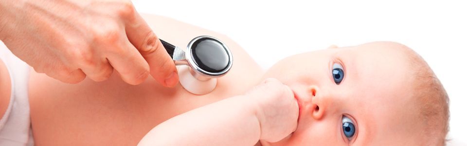 Un médico usa un estetoscopio sobre el pecho de un bebé. El bebé tiene ojos azules y mira hacia arriba.