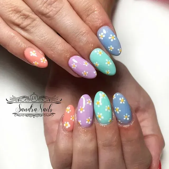 Las uñas de una mujer están pintadas de diferentes colores y tienen flores.