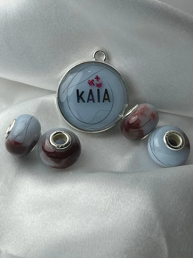 Un collar con el nombre Kaia está sobre una tela blanca.