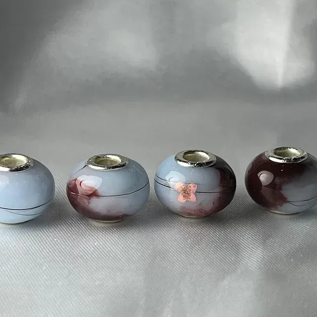 Cuatro cuentas de cerámica están alineadas en fila sobre una mesa.