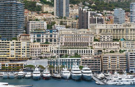 A group of boats are docked in a harbor in front of a city.