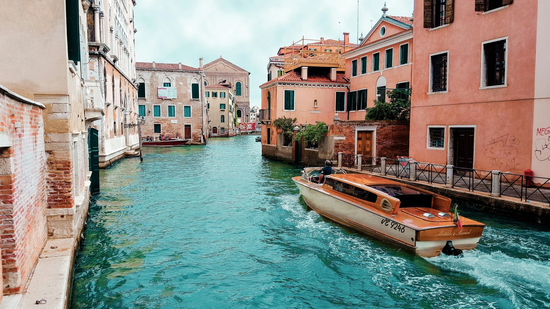 A boat is floating down a canal between two buildings.