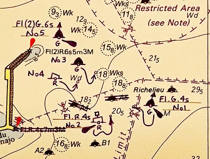 Una carta náutica detallada que muestra boyas de navegación, balizas, restos de naufragios y niveles de profundidad del agua alrededor de una zona portuaria costera.