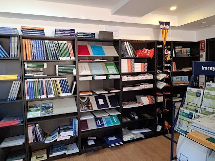 Varias estanterías repletas de libros, manuales y carpetas en una tienda u oficina bien iluminada.