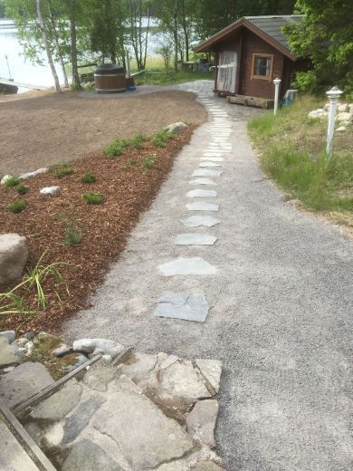 Kivilaatoista rakennettu polku mökin saunalle