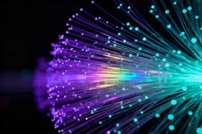 Estelas abstractas de luz de neón en tonos púrpura, cian y azul que irradian sobre un fondo negro.