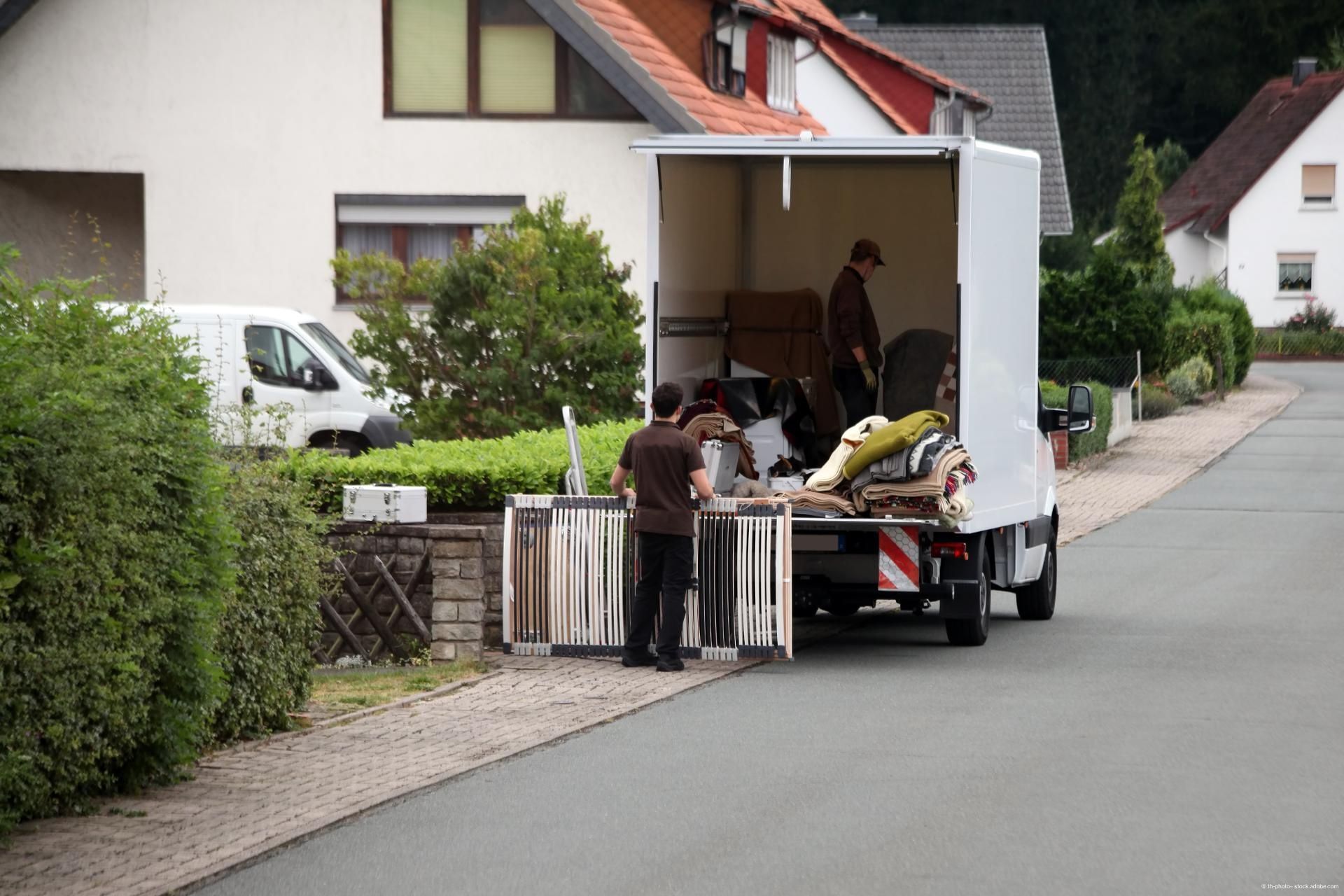 Ein Umzugs-LKW steht halbbeladen am Rand einer Straße und wird von zwei Männern eingeräumt