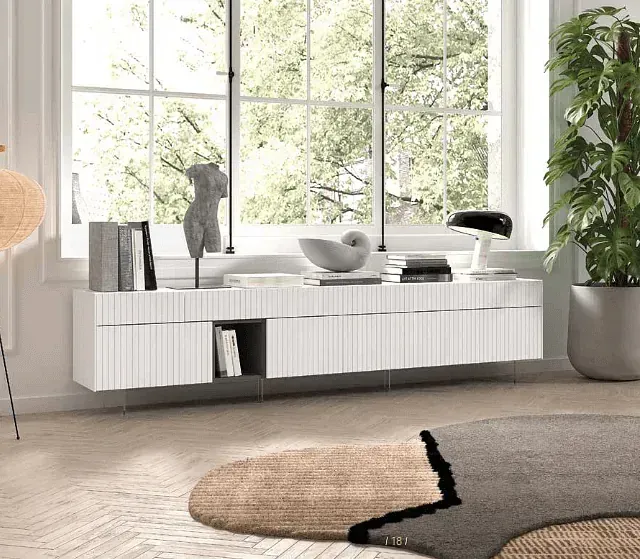 Una sala de estar con muebles blancos, una alfombra, una planta y una ventana.