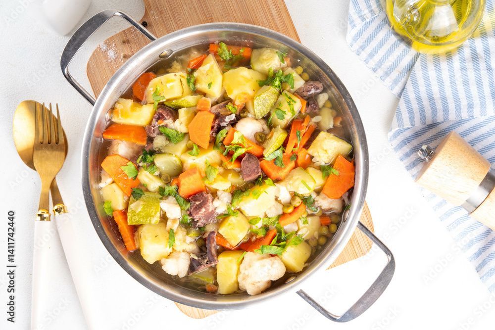 Vue aérienne d'un pot en métal rempli de légumes cuits sur une planche de bois.