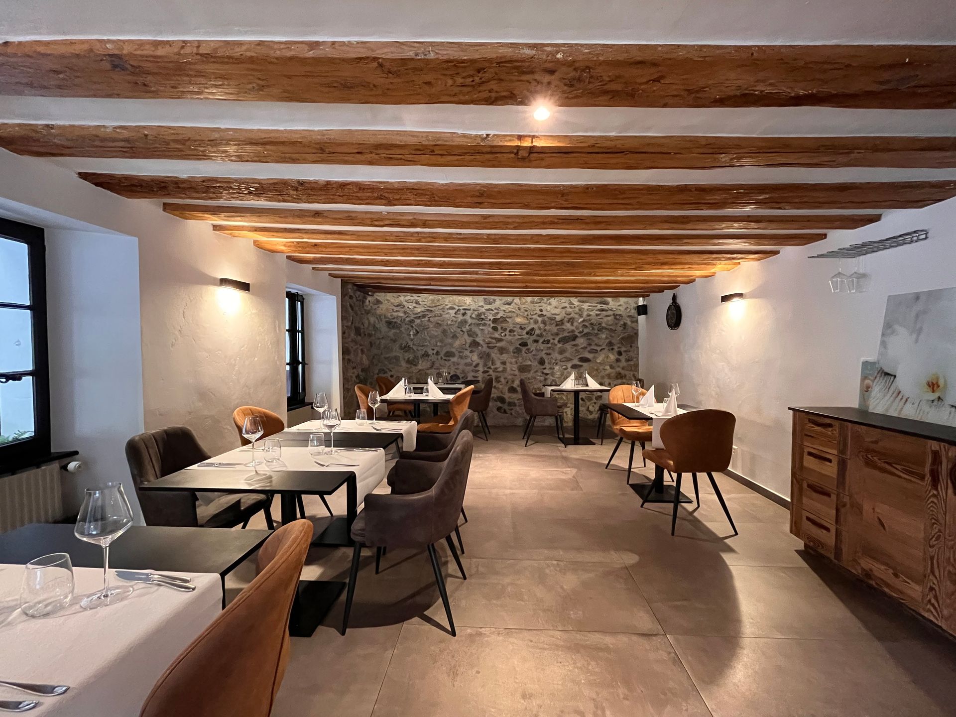 Intérieur de restaurant avec boiseries, tables, chaises et suspensions.