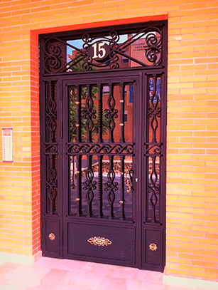 Una puerta negra con el número 15 está en una pared de ladrillos.