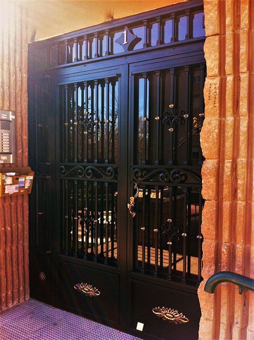 Una puerta de hierro forjado con una pared de ladrillos detrás de ella.