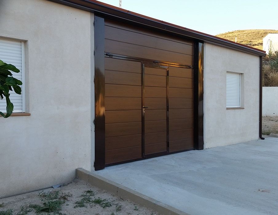 Una puerta de garaje marrón está en el costado de una casa.
