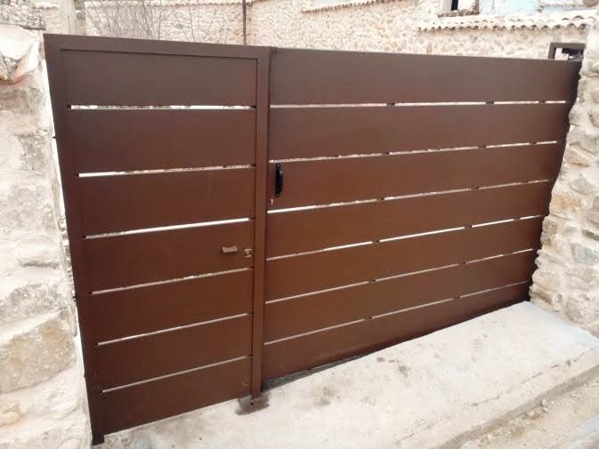 Una puerta marrón con un muro de piedra detrás.