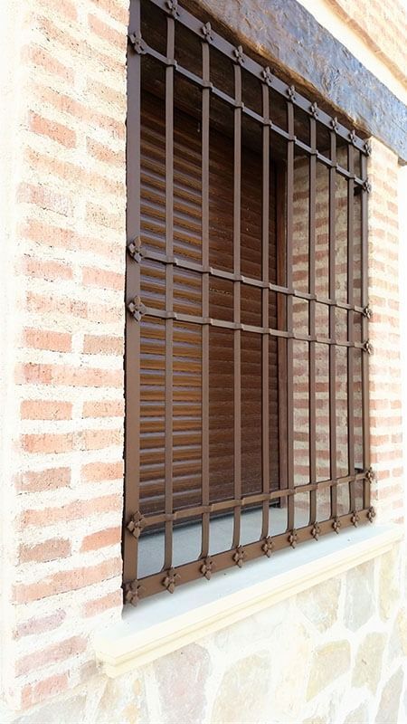 Una ventana con reja de hierro forjado en una pared de ladrillos.