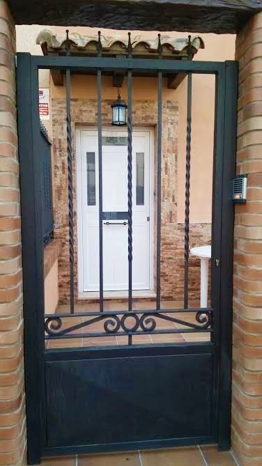 Una puerta negra que conduce a una puerta blanca con una pared de ladrillos detrás de ella.