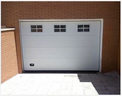 Una puerta de garaje blanca con una pared de ladrillos detrás.