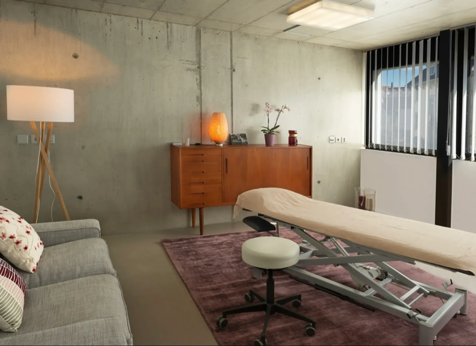 Frau hält ein Baby und ermutigt es zum Krabbeln; beide sind im Haus. Das Baby schaut leicht überrascht in die Kamera.