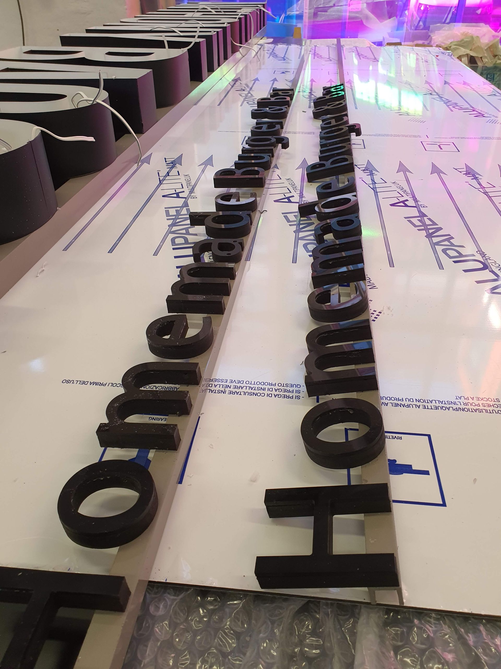 Lange Reihe schwarzer Einzelbuchstaben auf einer Arbeitsfläche mit Beleuchtung.