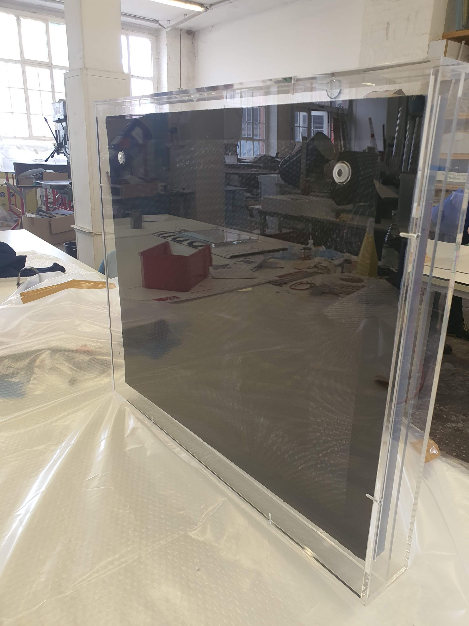 Großformatige, transparente Acrylscheibe in einer Werkstatt aufgestellt.