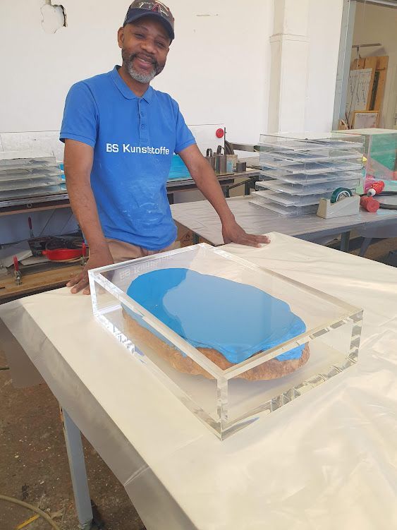 Mitarbeiter steht an einer Werkbank mit gestapelten Kunststoffplatten.