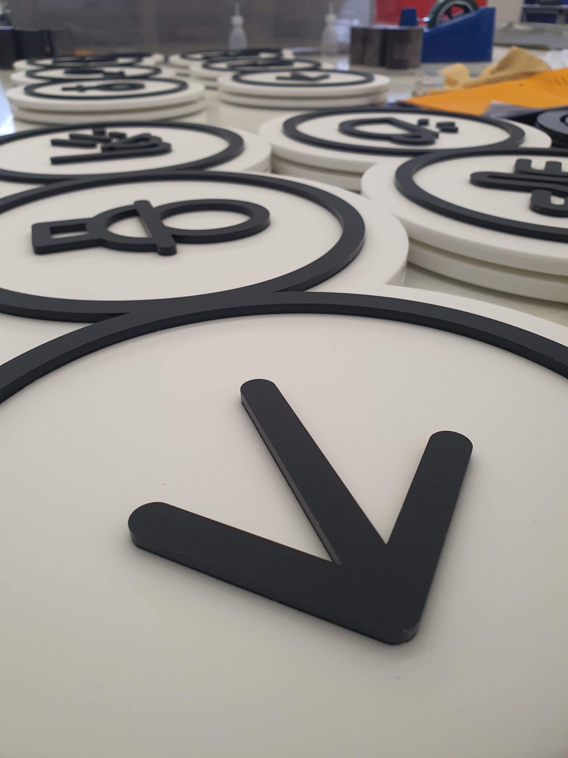 Mehrere runde, weiße Kunststoffplatten mit schwarzen Symbolen, nebeneinander angeordnet.