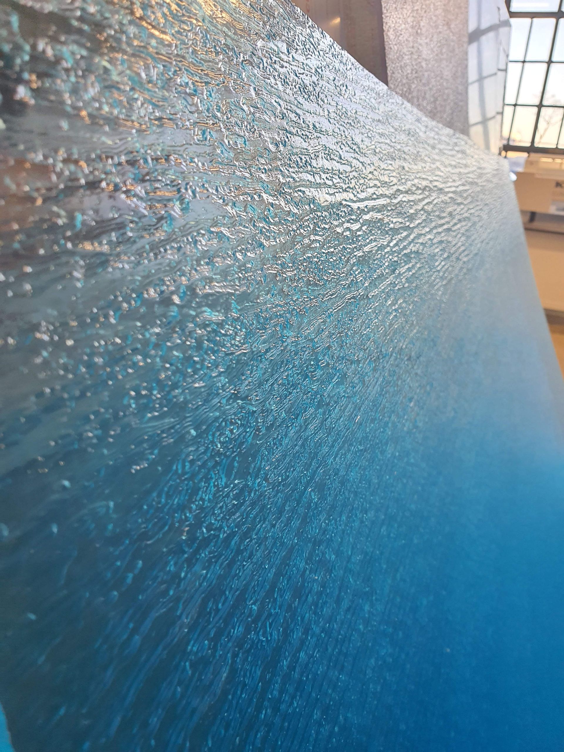 Nahaufnahme einer strukturierten, bläulich-transparenten Oberfläche mit unregelmäßiger Textur.