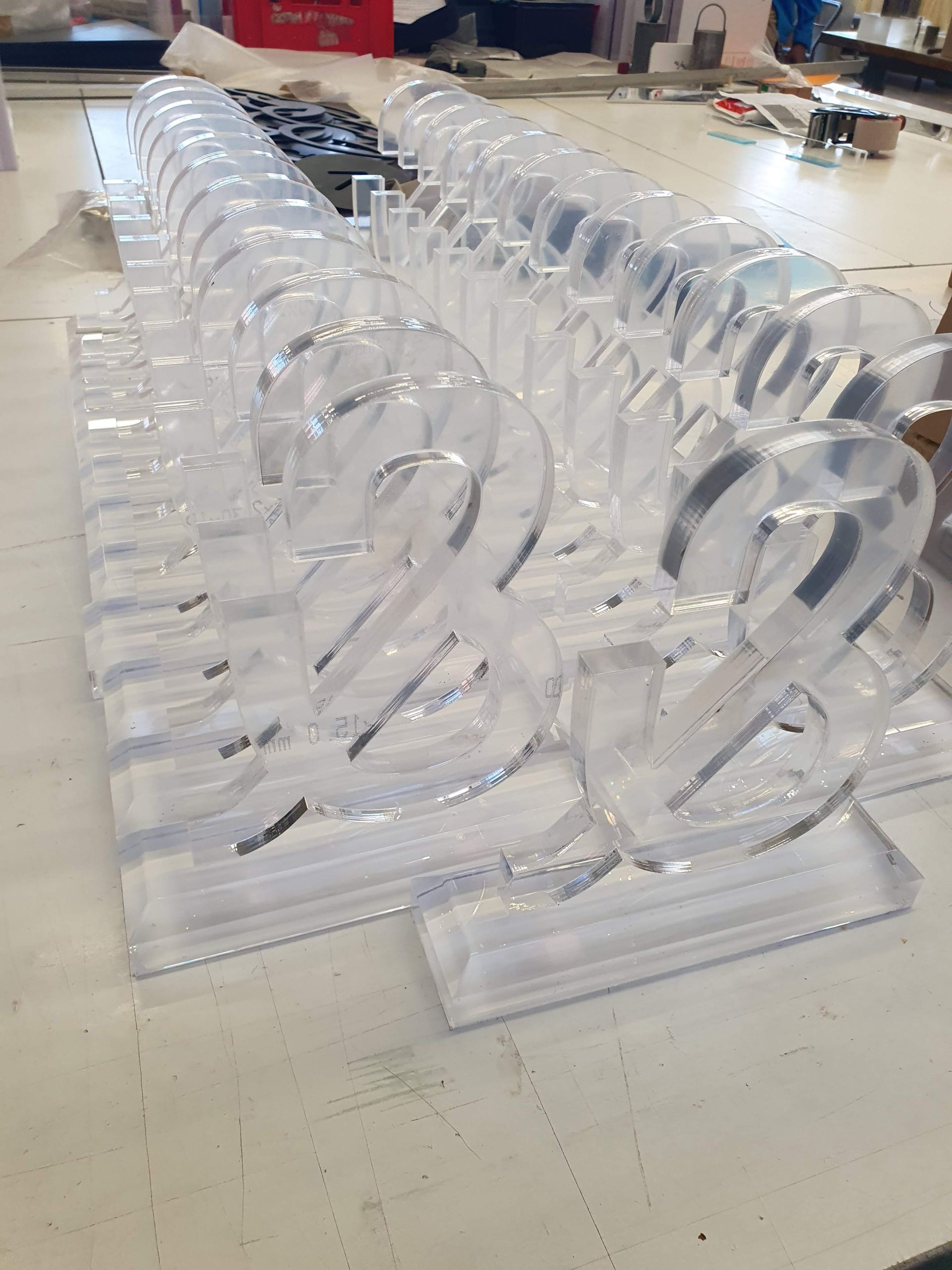 Reihe transparenter, runder Kunststoffteile auf einer Werkbank angeordnet.