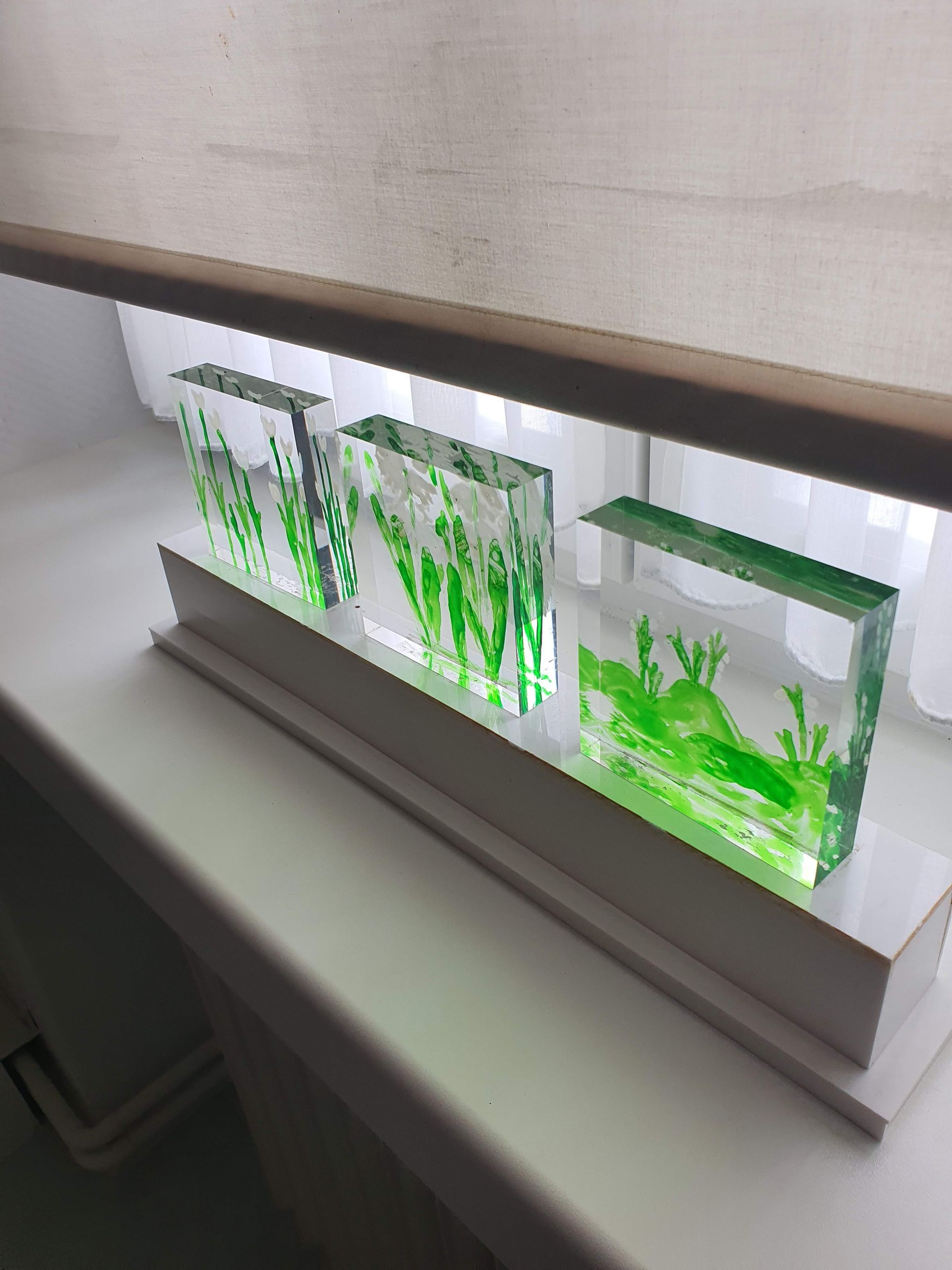 Transparente, grünliche Acrylplatten hinter einer Fensterbank gestapelt.