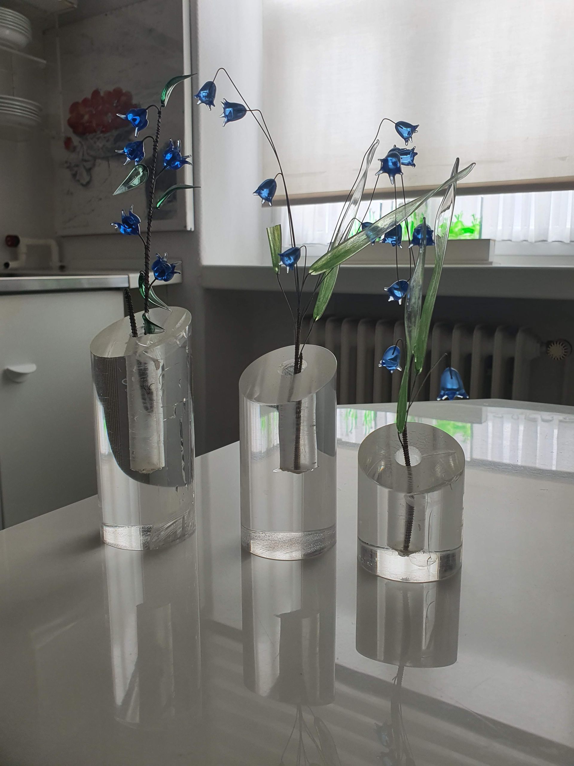 Filigrane, drahtartige Skulpturen mit kleinen blauen Blüten