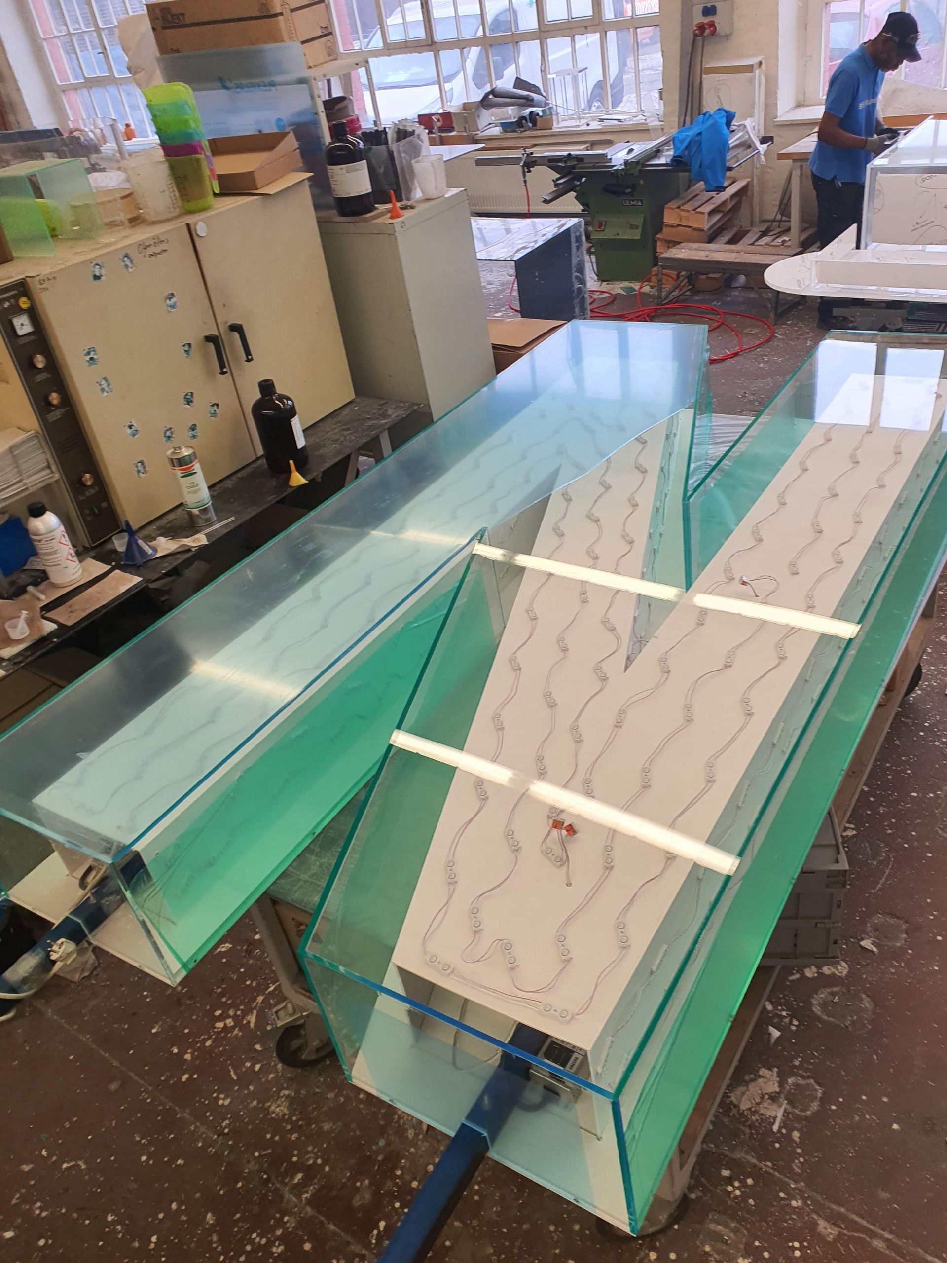 Große Glas- oder Acrylplatten auf Arbeitstischen in einer Werkstatt.