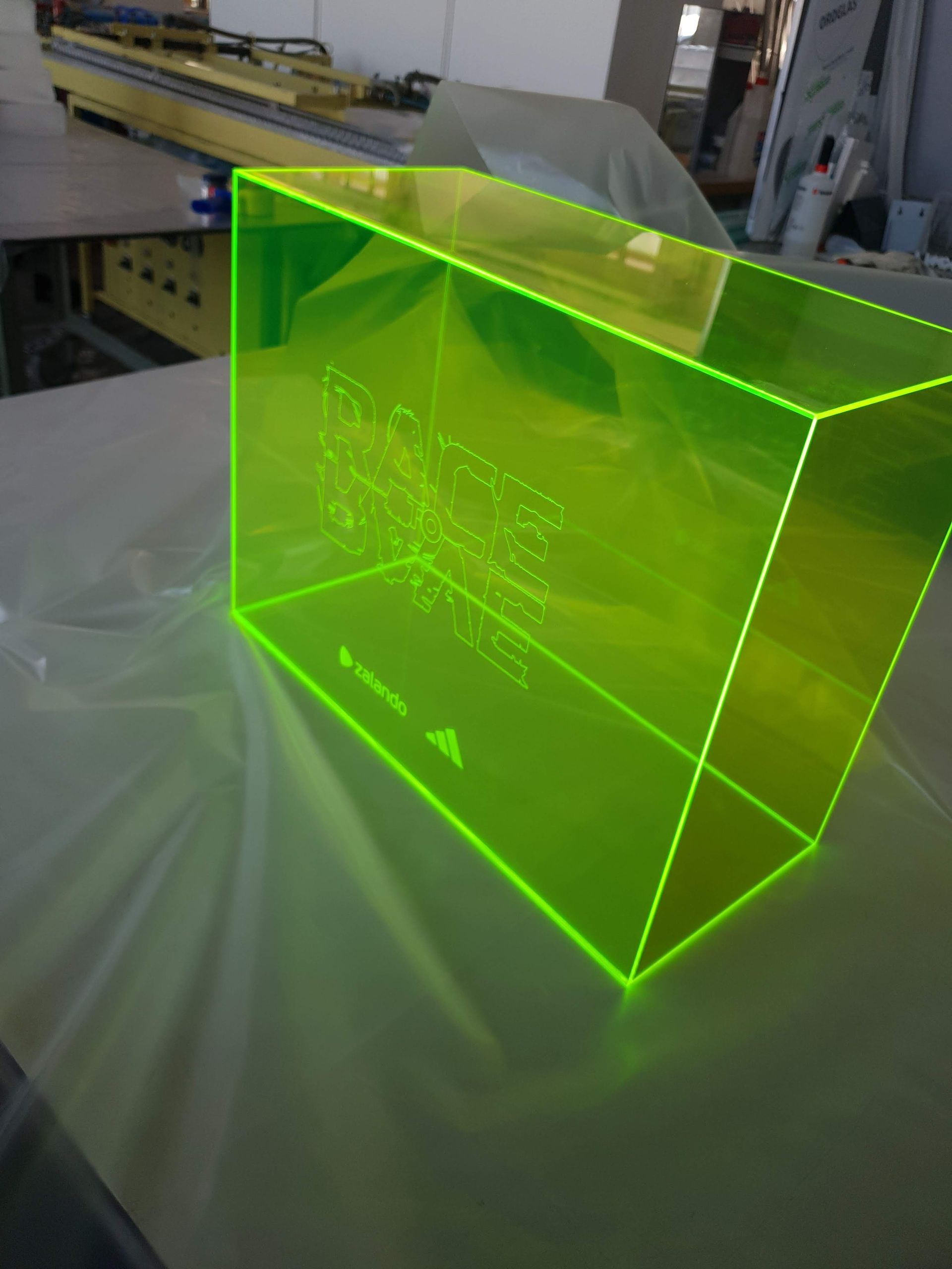 Transparenter, grün leuchtender Kunststoffwürfel mit eingraviertem Schriftzug.