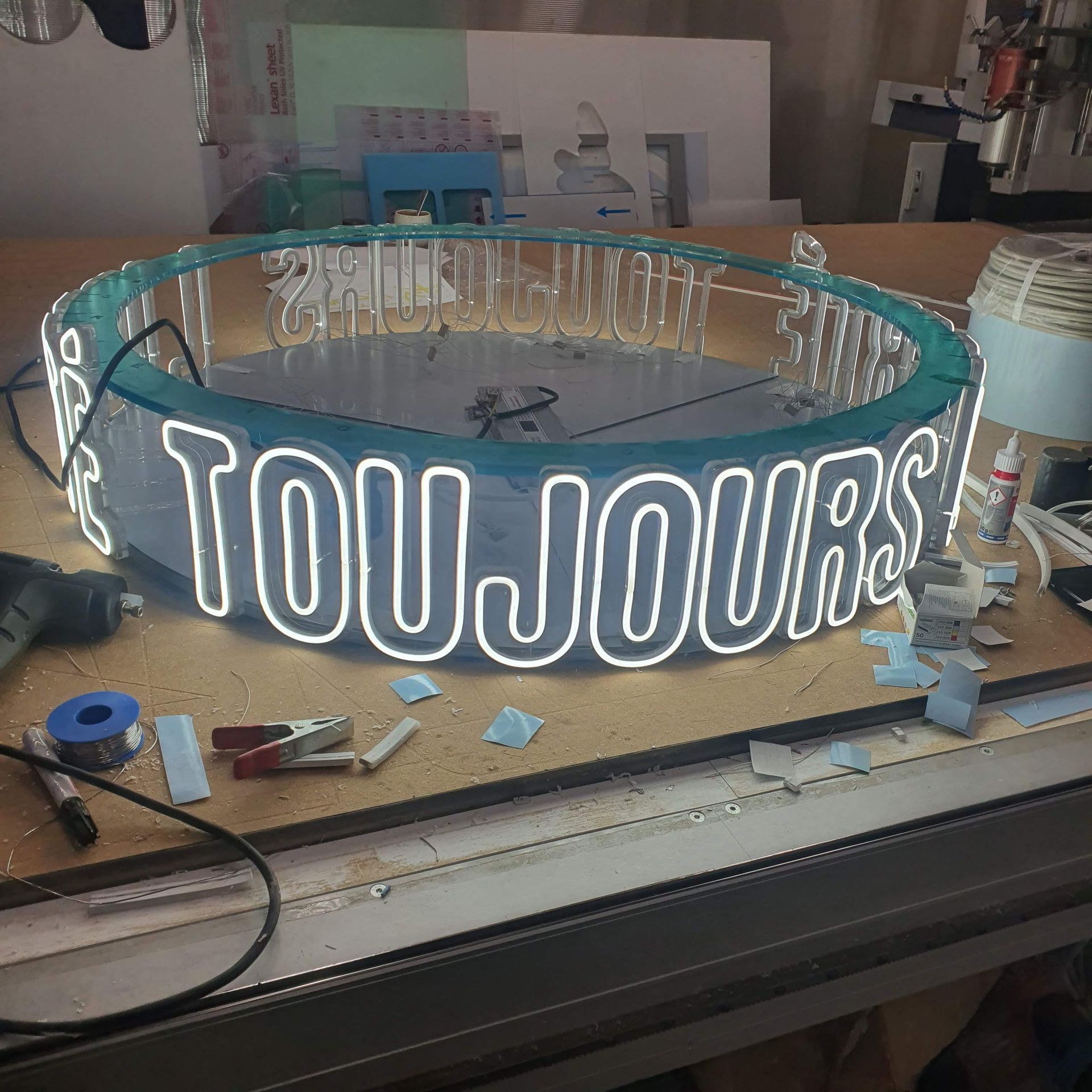 Ovales Neon-Schild mit weißem Schriftzug,in einer Werkstatt.