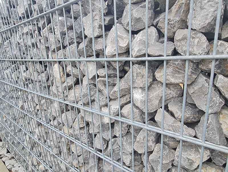 Eine Nahaufnahme eines Maschendrahtzauns voller Steine.