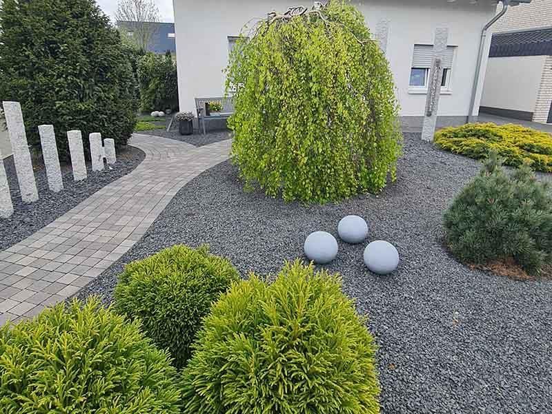 Ein Garten mit einem weißen Haus im Hintergrund und einem Weg, der dorthin führt.