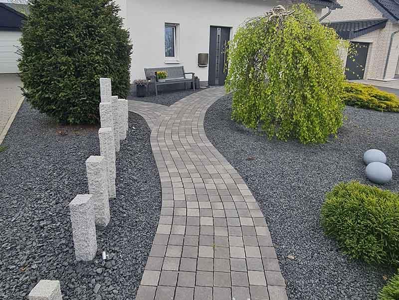 Ein Ziegelweg, der zu einem Haus in einem Garten führt.