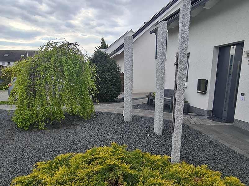 Ein weißes Haus mit einer Trauerweide davor.