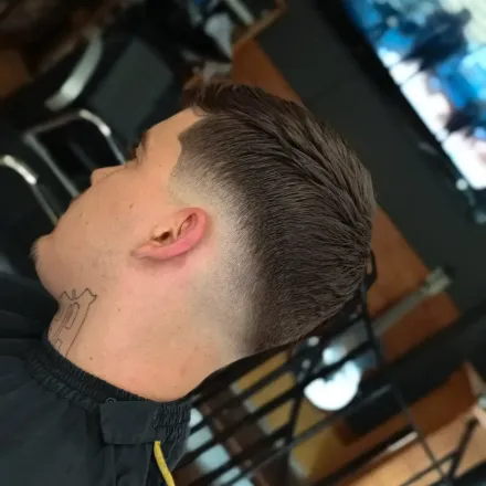 Un hombre con un tatuaje en el cuello está sentado frente a un televisor.