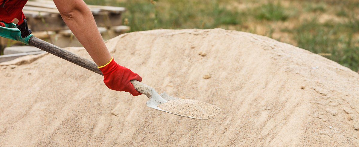Ouvrier soulevant une pelle de sable