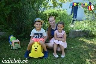 Eine Frau kniet neben zwei Kindern und einem Spielzeughund.