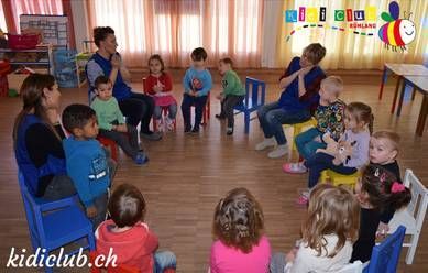 Eine Gruppe von Kindern sitzt in einem Raum im Kreis.