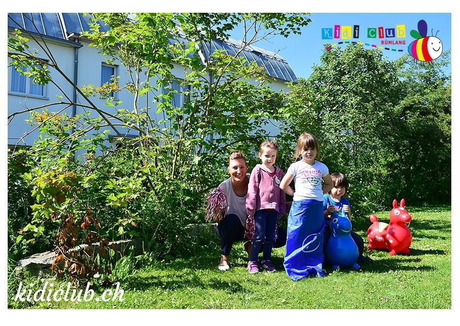 Eine Gruppe Kinder spielt in einem Hof ​​und eine Frau kniet nieder.