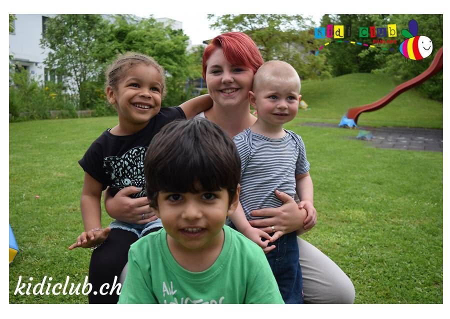 Eine Frau hält drei Kinder in einem Park mit einer Rutsche im Hintergrund