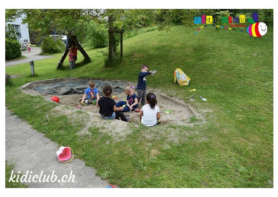 Eine Gruppe Kinder spielt in einem Sandkasten.